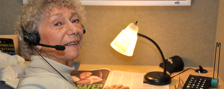 an image of an older woman wearing a headset as she reads for Access News