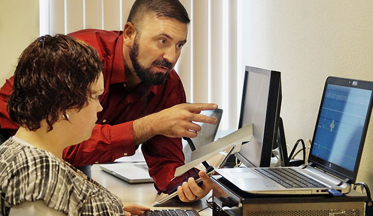 an image of two people at a computer using assistive technology