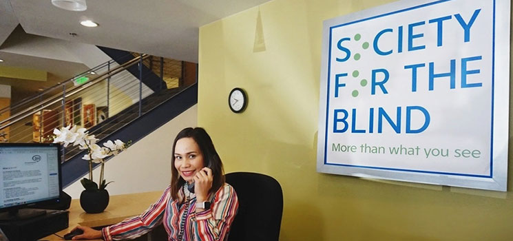 an image of the front desk receptionist sitting behind the reception counter in the lobby of the Society for the Blind building