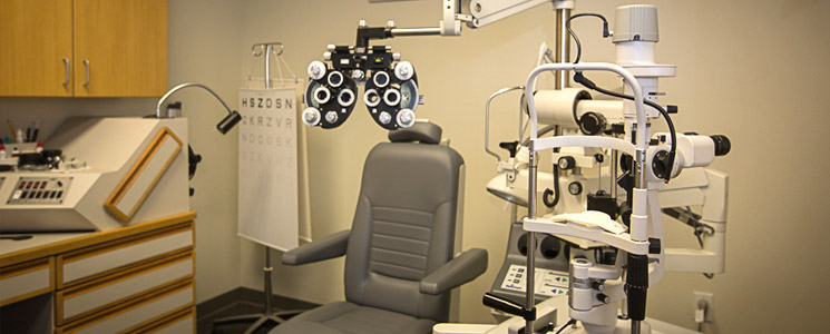 an image of the exam room with a large gray chair and some low vision evaluation equipment