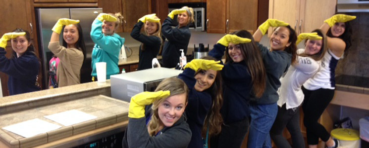 an image of a group of volunteers with yellow dishwashing gloves on standing around a kitchen