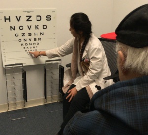 Dr. Wong pointing to an eye chart; patient looks in the direction of the eye chart.
