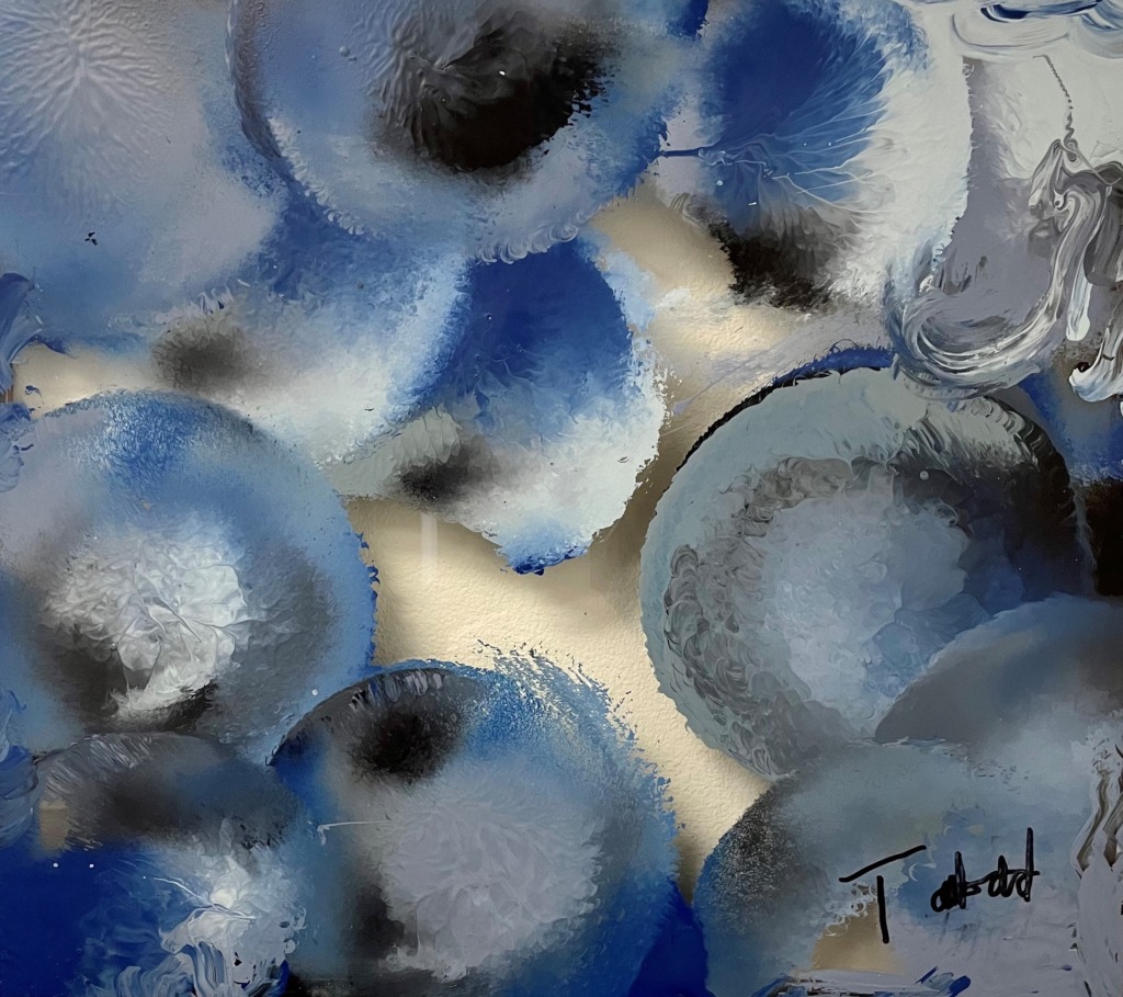 Painting by Tim Taubold, Medium acrylic paint on Glass. Navy, Ultramarine, and Electric blue splashes of paint bloom into larger circles of periwinkle and light gray paint. The layered blooms overlap each other like an arrangement of flowers leaving clear negative space of the glass in the center of the painting.