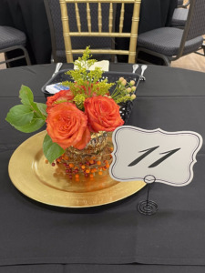 Briggs Award Event Centerpiece: a gold votive with orange roses and green foliage