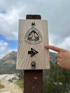 A sign with the Pacific Coast Trail logo and an arrow pointing right
